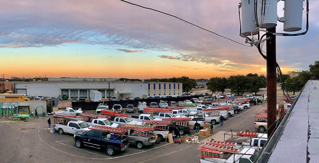 An aerial view of a large fleet of service trucks with ladders, ready for jobs at Crest Electrical Solutions in Arlington, TX.