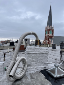 A flexible metal chimney liner coiled on a rooftop for installation by Chimney Sweep Service LLC in Brooklyn, NY.