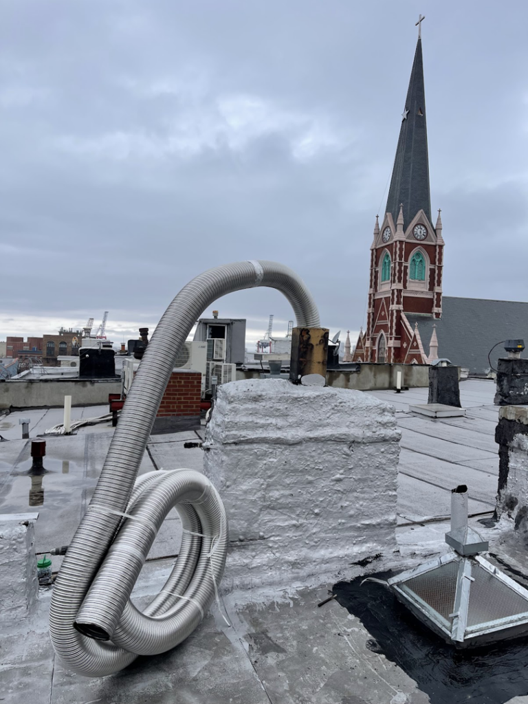 A flexible metal chimney liner coiled on a rooftop for installation by Chimney Sweep Service LLC in Brooklyn, NY.