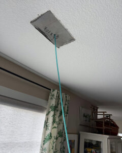 A flexible hose extending from a ceiling air vent during service by Green Seal Energy in Overland Park, KS.