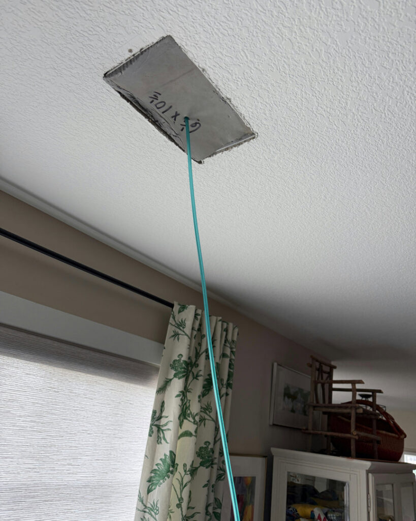 A flexible hose extending from a ceiling air vent during service by Green Seal Energy in Overland Park, KS.
