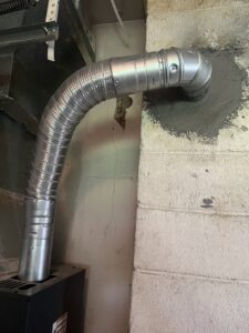 Flexible metal ductwork installed through a wall by Absolute Comfort Heating & Cooling, Inc. in Virginia Beach, VA.