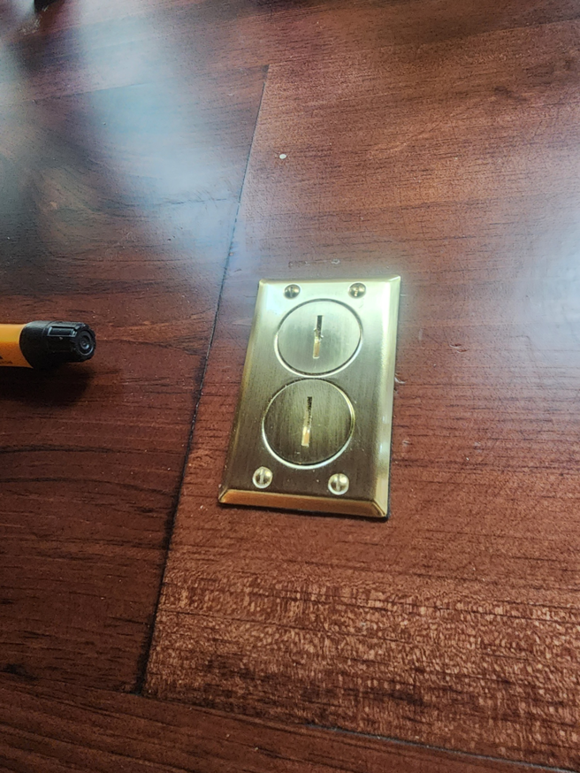Brass floor electrical outlet installed on a wooden floor by D&R Construction & Electrical Services in Summerville, SC.