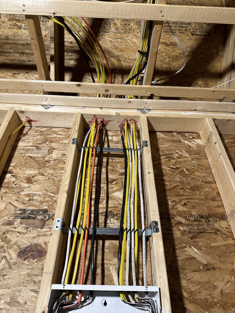 Neatly installed electrical wiring running through floor joists and into an electrical box by RAD-WIRE ELECTRIC, LLC in Manchester, NH.