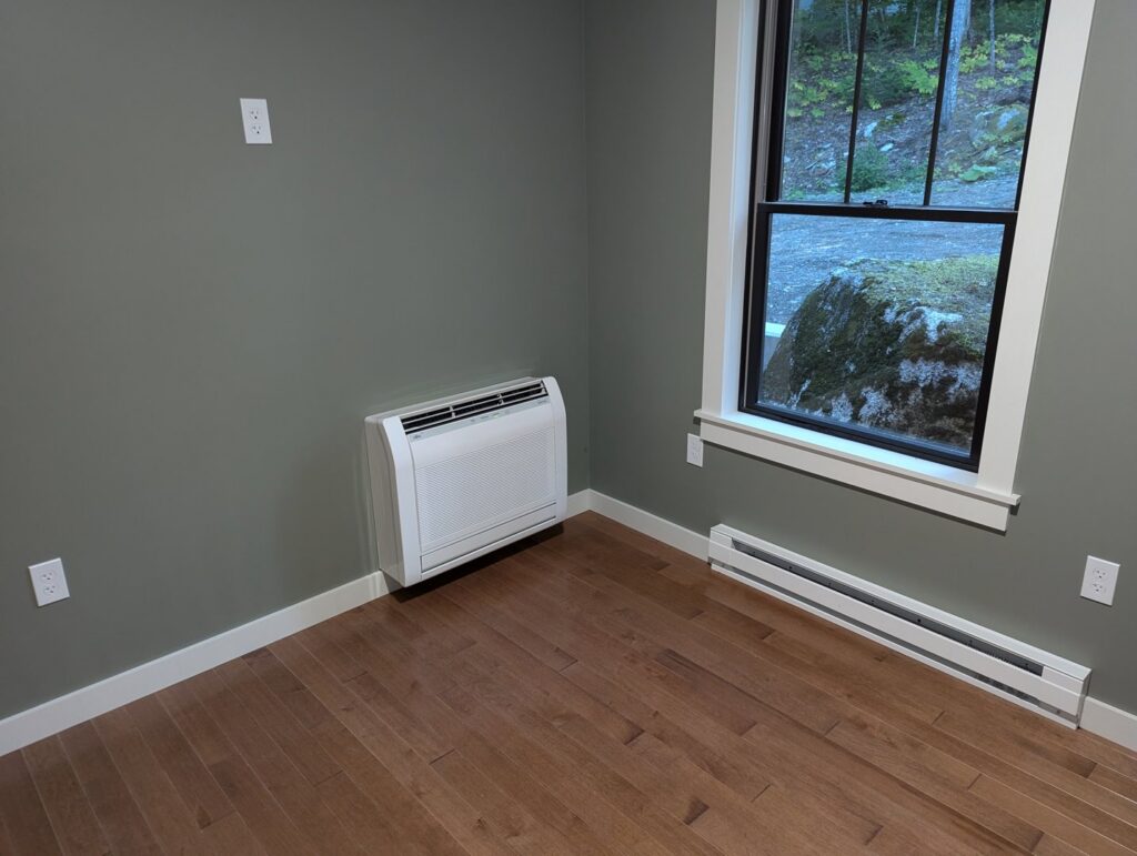 A floor-mounted heat pump unit installed in a finished room by Kinney Family Heat Pumps in Augusta, ME.