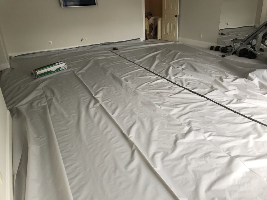 A room with floors covered for protection during insulation work, part of wildlife remediation by The Squirrel Guys in Birmingham, AL.