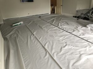 A room with floors covered for protection during insulation work, part of wildlife remediation by The Squirrel Guys in Birmingham, AL.