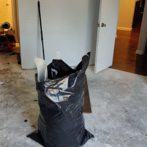 A large black bag filled with debris from old flooring removal by Steam Vs. Soil Carpet Cleaning in San Diego, CA