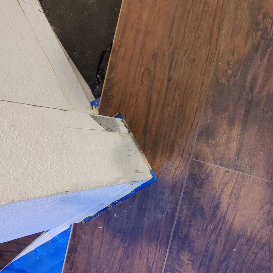 Detailed view of new laminate flooring installed along a wall edge with blue tape by Steam Vs. Soil Carpet Cleaning in San Diego, CA