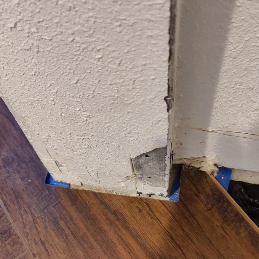 New laminate flooring installed around a doorframe with blue tape by Steam Vs. Soil Carpet Cleaning in San Diego, CA