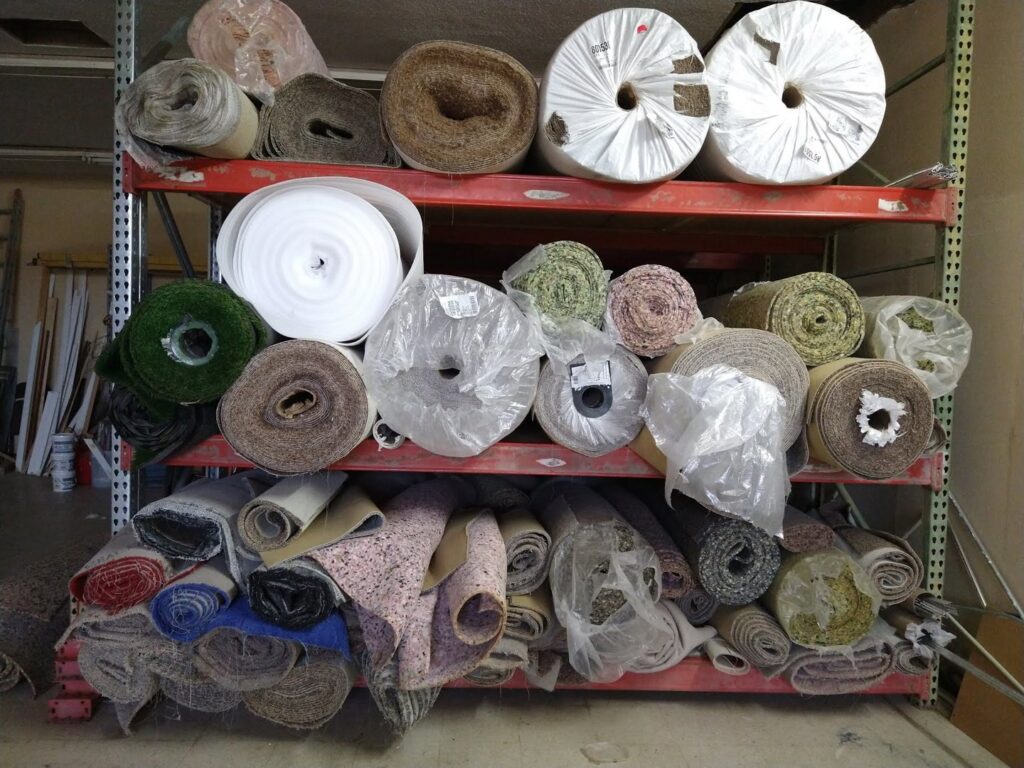 Rolls of carpet, turf, and other flooring materials stored in the Carpets Texas warehouse in El Paso, TX.