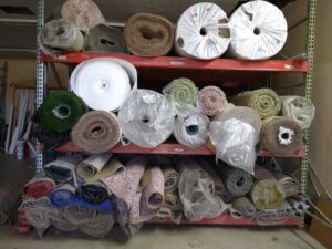 Rolls of carpet, turf, and other flooring materials stored in the Carpets Texas warehouse in El Paso, TX.