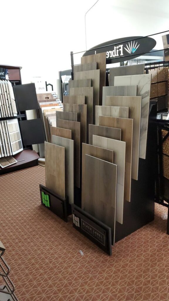 A display stand showcasing various flooring tile and plank samples at Discount Carpet Brokers in Scottsdale, AZ