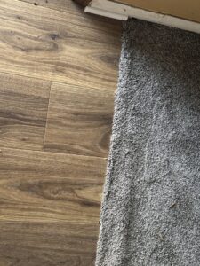 A close-up view of a seamless flooring transition from wood-look planks to carpet by Carpet Warehouse in Lafayette, IN.