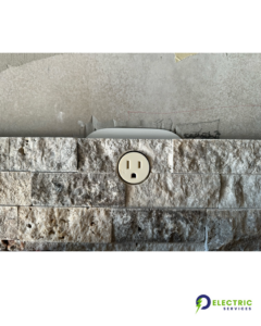 A flush-mounted electrical outlet expertly installed in a stone wall by O Electric Services in Dallas, TX.