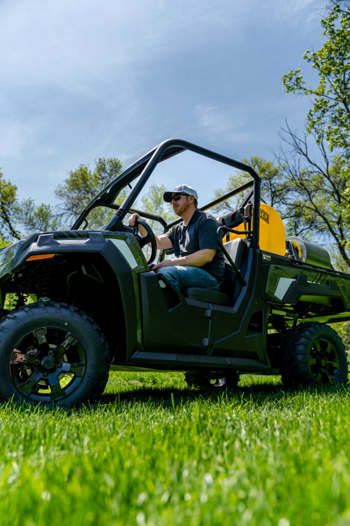 A Fog'em Mosquito Control technician driving a utility vehicle equipped with a sprayer for pest control services in Bismarck, ND.