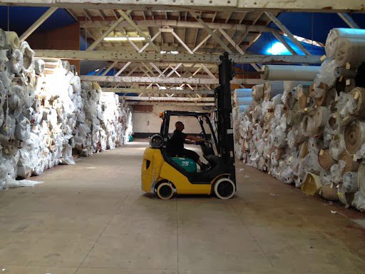 A forklift operating in a warehouse filled with rolls of carpet at Mill Sales Co. in Los Angeles, CA