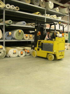 A forklift operating in the warehouse, surrounded by rolls of carpet at Craft Rug Mills in Easton, PA.