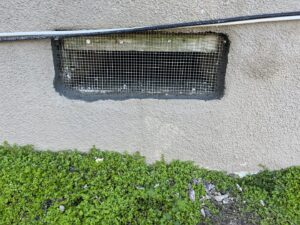 A foundation vent sealed with wire mesh and cement for pest exclusion by Ark Pest Management in Anaheim, CA.