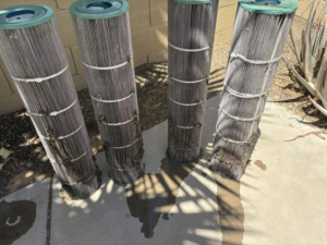 Four dirty pool filter cartridges lined up, ready for cleaning or replacement by Aquatec Pool Care in Jacksonville, FL.