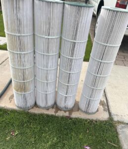 Four dirty pool filters standing on the ground, indicating a need for cleaning or replacement by Edward's Pool Service, LLC in Gilbert, AZ.