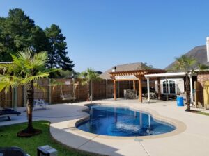 A beautiful freeform backyard swimming pool with concrete patio and landscaping by Central Pools, Inc. in Baton Rouge, LA.