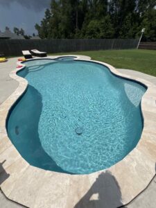 A sparkling clean freeform swimming pool with a visible pool cleaner hose, demonstrating maintenance by La Pool Pro LLC in New Orleans, LA.