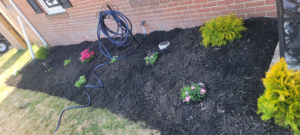 A newly mulched flower bed with fresh plantings next to a brick house, showcasing work by Parks' Lawn Care in Hagerstown, MD.