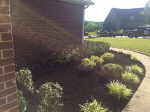 Freshly mulched landscaping beds with a lawn care truck and trailer in the background by Cutting Edge Lawn Services in Islip, NY