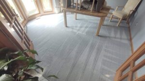 A freshly cleaned grey carpet with distinct cleaning lines in a living room by Dry Green Cleaning in Detroit, MI.