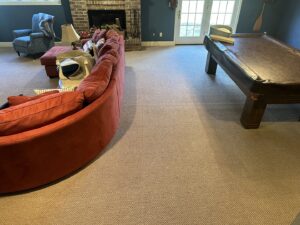 Freshly cleaned carpet in a living room with a red sofa by Monarch Cleaning Solutions in Parkville, MO