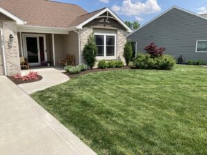 A freshly cut and well-maintained residential lawn with mulched flower beds by Three Rivers Lawn Care Co. in Fort Wayne, IN.