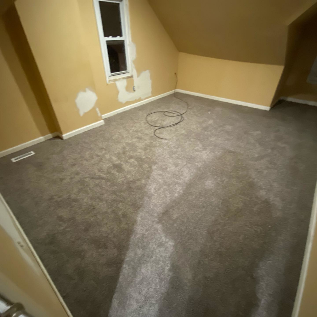 A renovated room with freshly installed grey carpet, showcasing a completed project by HK Carpet Doctors in Sterling Heights, MI