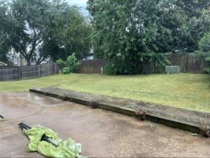 A freshly mowed backyard lawn with visible stripes on a rainy day, demonstrating completed work by Lande Lawn Care in Broken Arrow, OK.