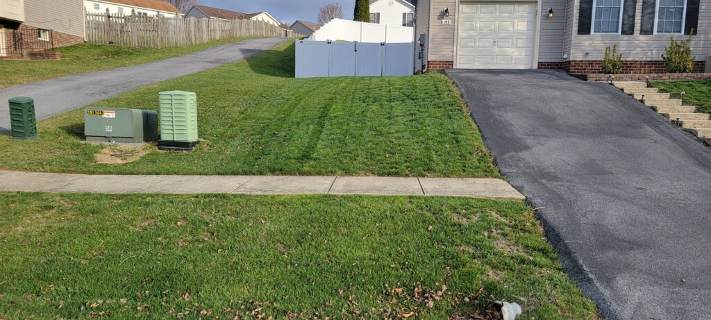 A freshly mowed front lawn with clean stripes next to a driveway and sidewalk, completed by Parks' Lawn Care in Hagerstown, MD.