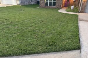 A well-maintained front yard with a freshly mowed lawn, showcasing professional service from Lawns Plus More LLC in Edmond, OK.