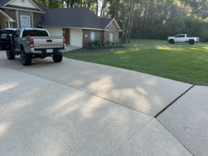 A freshly mowed green lawn next to a residential home, showcasing lawn care services by Caddo Power Cleaning & Lawn Care in Shreveport, LA.