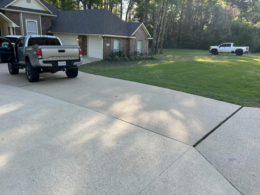 A freshly mowed green lawn next to a residential home, showcasing lawn care services by Caddo Power Cleaning & Lawn Care in Shreveport, LA.