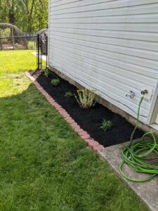 A freshly mulched flower bed with new plants installed by Kustom Lawn Kare LLC in Greenwood, IN.