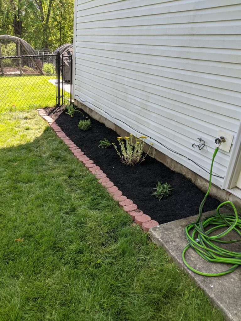 A freshly mulched flower bed with new plants installed by Kustom Lawn Kare LLC in Greenwood, IN.