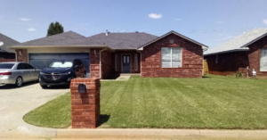 A beautifully mowed front lawn with crisp stripes at a brick house by You're Choice Lawn Care LLC in Oklahoma City, OK.