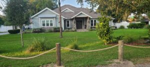 A decorative rope fence with wooden posts enhancing the curb appeal of a front yard, installed by Exacta FENCE LLC in Jacksonville, FL.