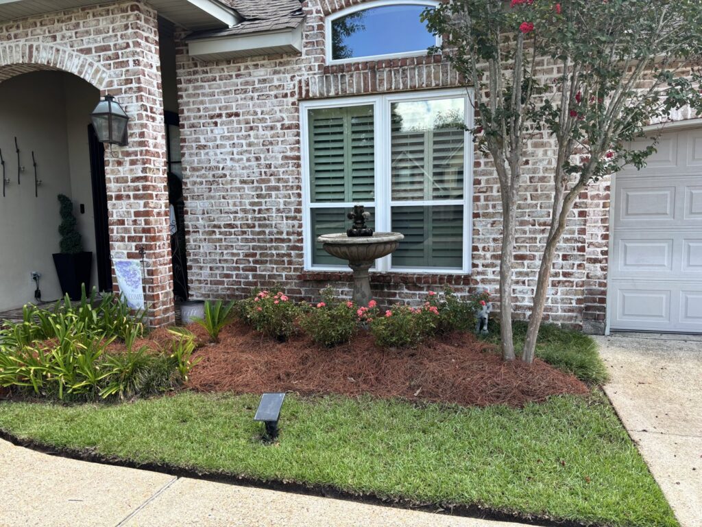 A front yard featuring a decorative fountain, mulched flower beds, and a well-kept lawn by Fresh Cuts Nola Lawn Service in New Orleans, LA.
