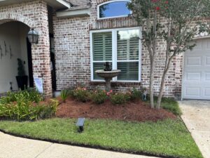A front yard featuring a decorative fountain, mulched flower beds, and a well-kept lawn by Fresh Cuts Nola Lawn Service in New Orleans, LA.