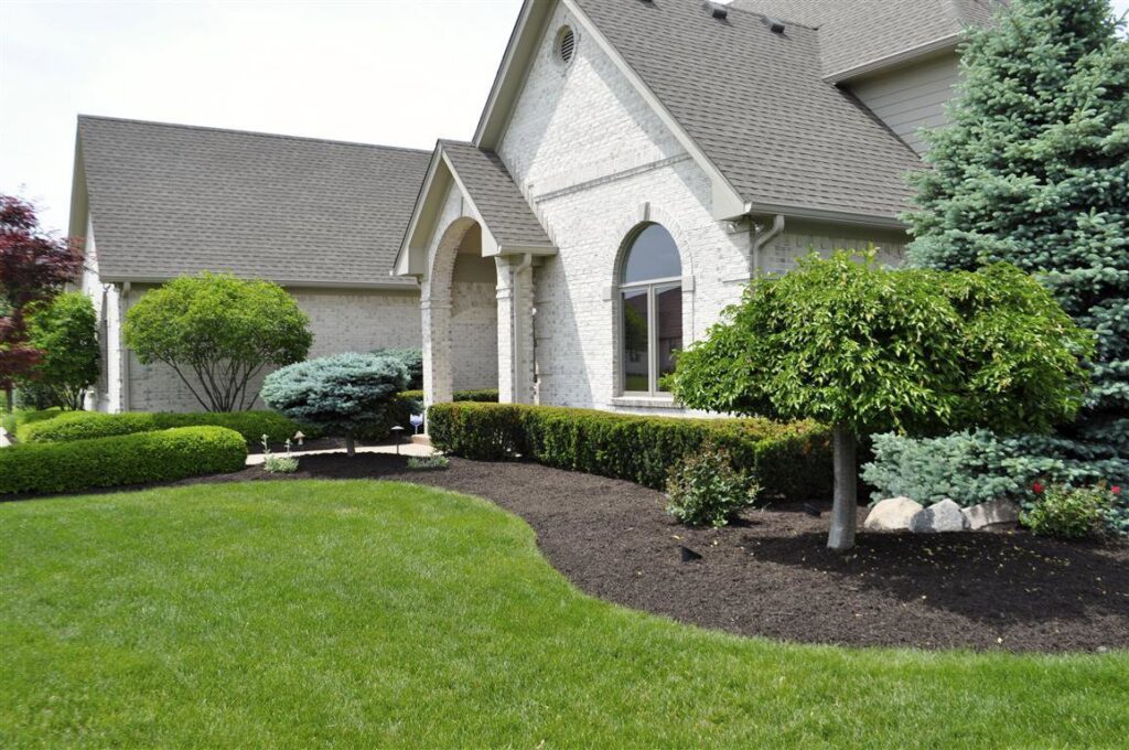 A pristine front yard with lush green lawn and manicured mulched beds by Kustom Lawn Kare LLC in Greenwood, IN.