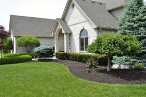 A pristine front yard with lush green lawn and manicured mulched beds by Kustom Lawn Kare LLC in Greenwood, IN.