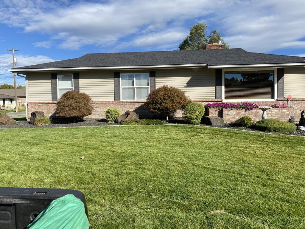 A beautifully maintained front yard with a lush green lawn and decorative landscaping, cared for by McLain Lawn & Landscape in Spokane, WA.