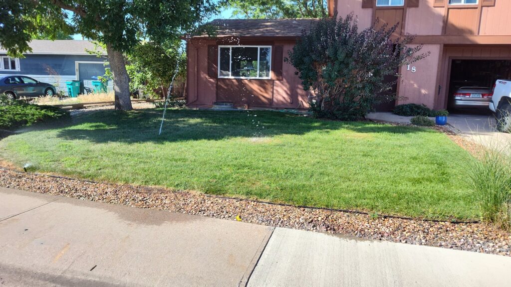 A front yard with a sprinkler system actively watering the lawn, maintained by Aaron's Lawn Service in Pittsburg, KS.