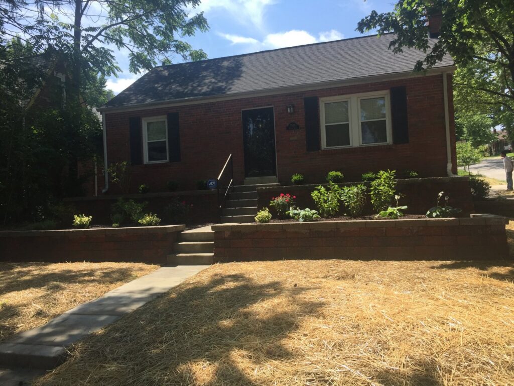 A front yard with straw covering the lawn and newly landscaped garden beds by Creamer Construction LLC in Saint Peters, MO.