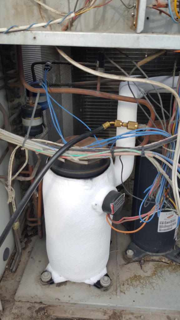 A frozen HVAC compressor unit with refrigerant lines, indicating a system issue by Air Conditioning and Heating Service of Meridian, ID